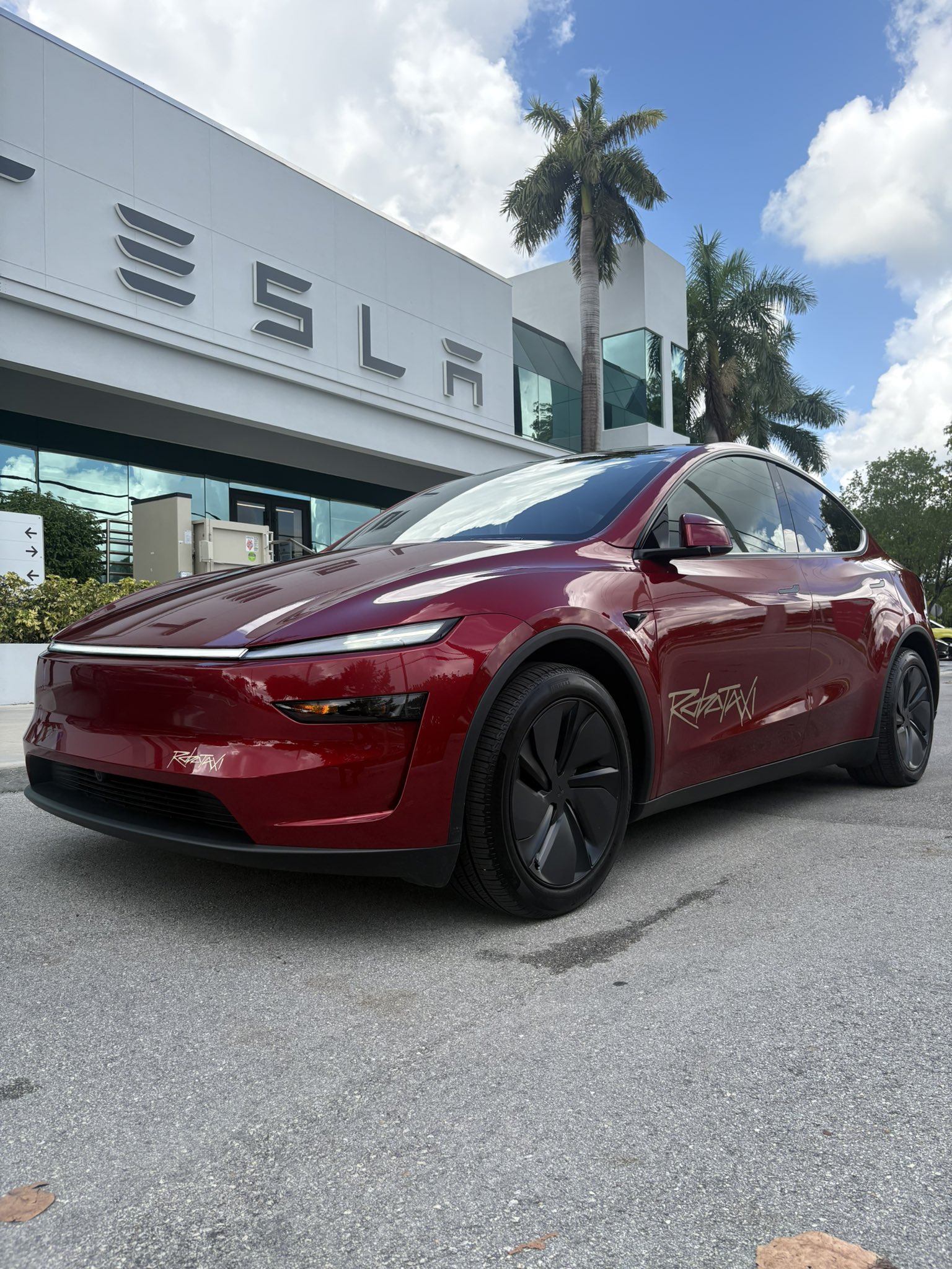 Tesla Robotaxi (Model Y) en Miami frente a una tienda Tesla